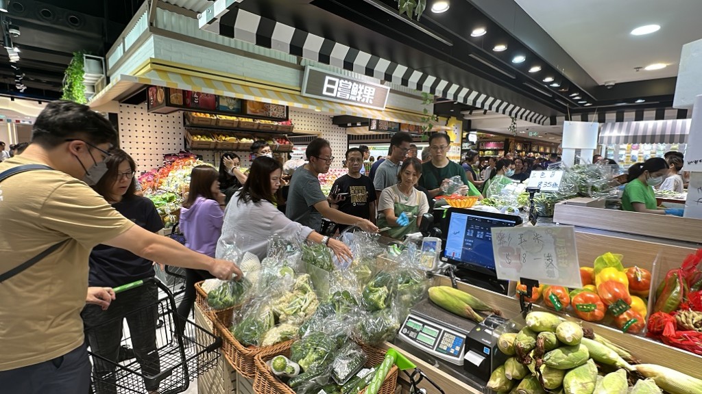 店员每摆放新蔬菜，客人立即上前抢购。(刘汉权摄)