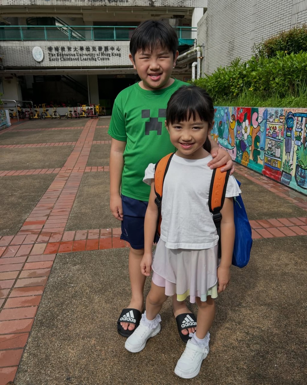 哥哥Tyler輕輕搭著妹妹Leah的肩膀，在幼稚園的校園內合照
