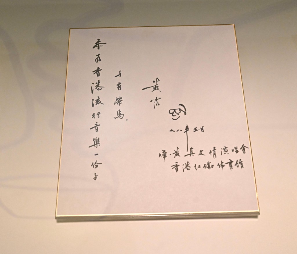《滄海一聲笑—黃霑》展覽展品：「煇·黃真友情演唱會」黃霑親筆簽名板，附黃霑的自畫像。（1998年5月）（香港歷史博物館藏品）