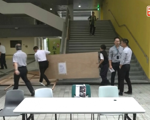 有職員清理被破壞的圍板。港台截圖
