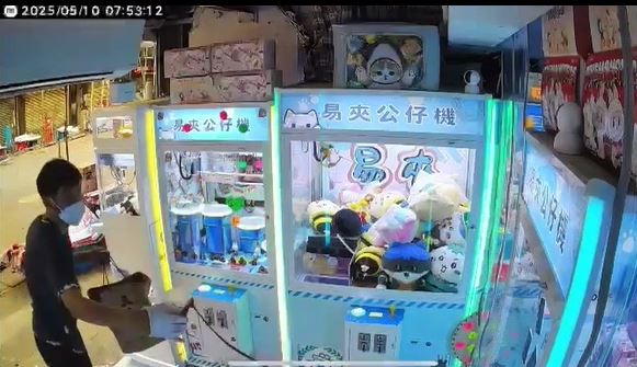 從袋中取出盛有紅油的紙杯向夾公仔機淋潑紅油。店主提供影片