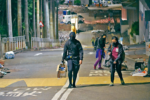 ■本校生撤離時，一名黑衣人仍手持放滿汽油彈的紙箱行往出口。