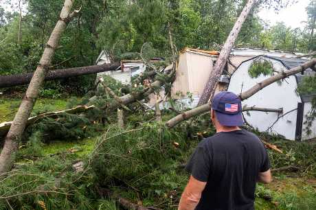 狂风吹倒大树，压住民居。美联社