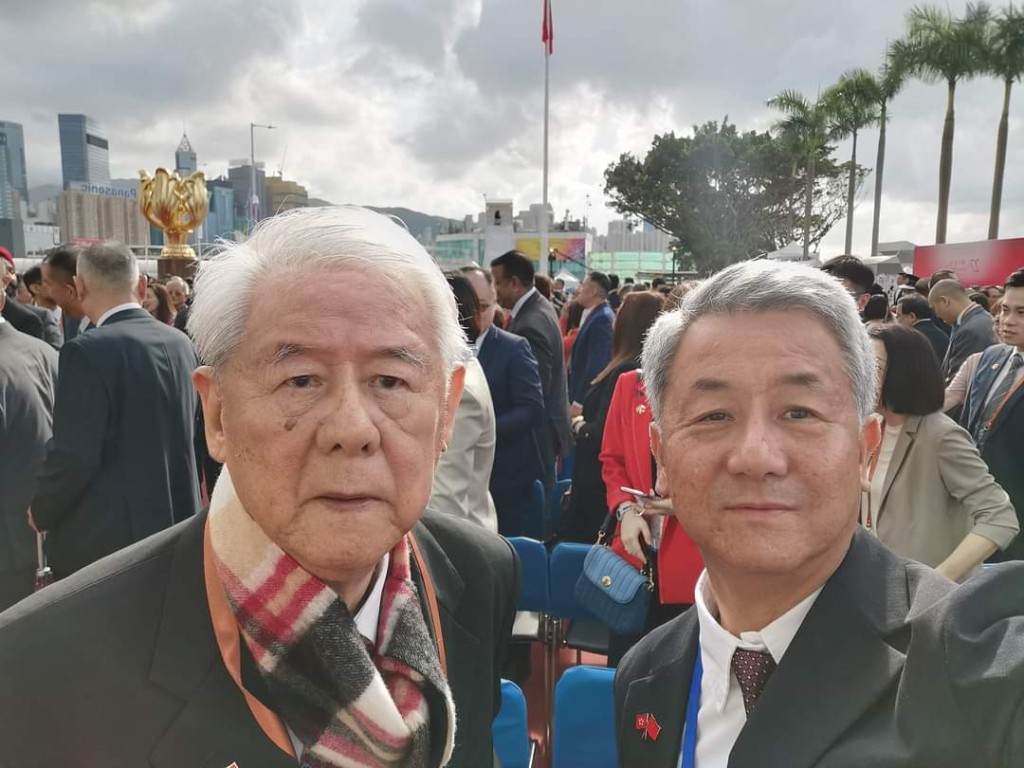 余国贤 (右) 与父亲余润兴观看升旗仪式。