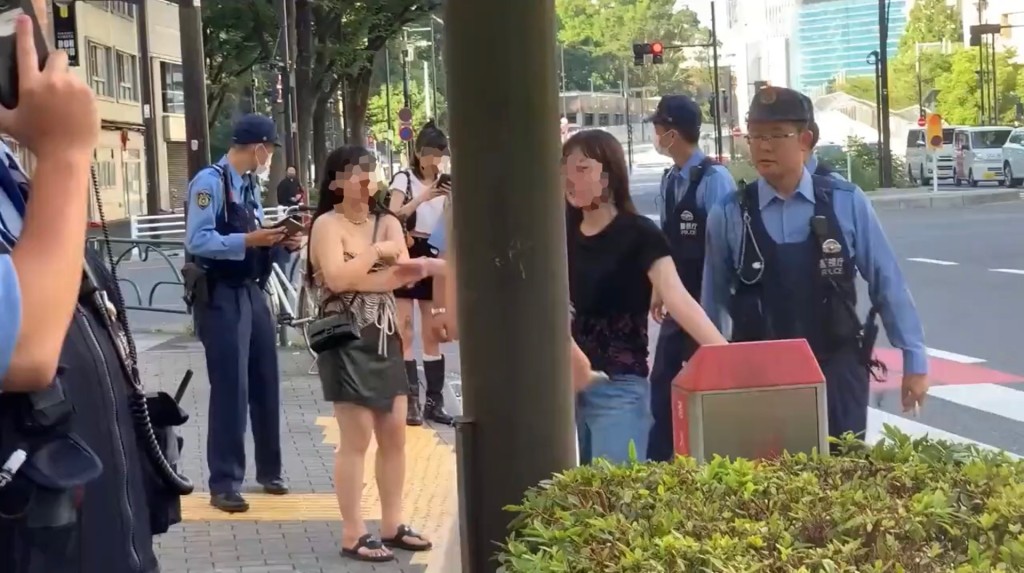 約5、6名警員與4名女子站在新宿一處街角。 