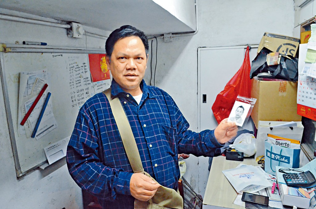 死者的胞弟王志明，展示兄长王志成的遗照。