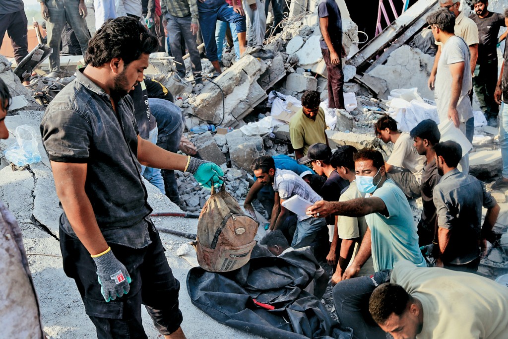 救援人員在瓦礫中拾起女學童的書包。