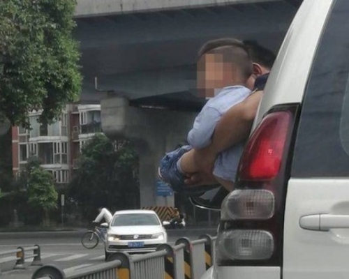 一名男子將尿急的男孩抱出車窗外解決。(網圖)