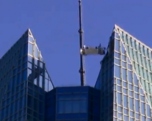 美國兩名洗窗工人進行清潔工作時，起重機突然故障，被吊在50層樓高空上來回擺盪。　網上圖片