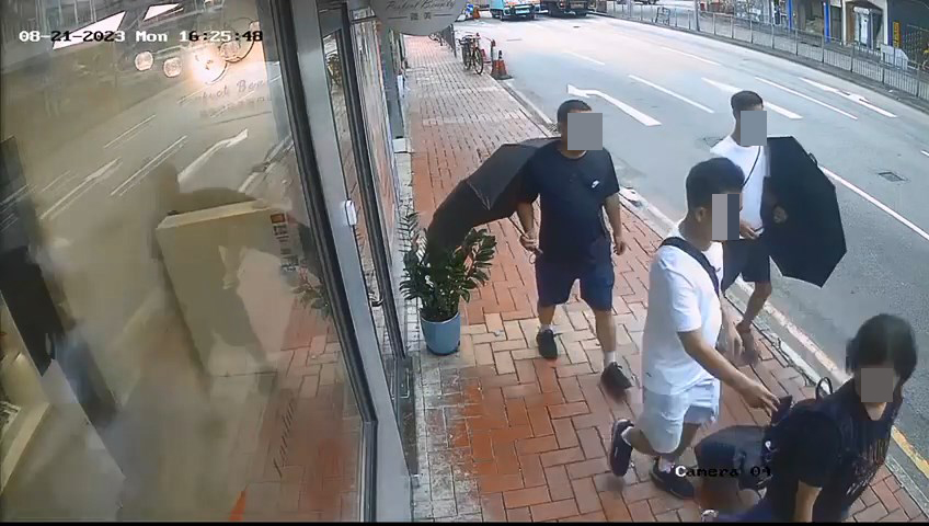 3名男子手持雨伞作遮掩，企图打开前方女子的背囊盗窃。