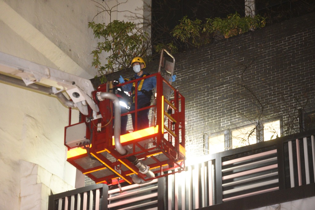 消防員利用升降台，將墮至三樓平台的女子救回室內位置。（尹敬堂攝）