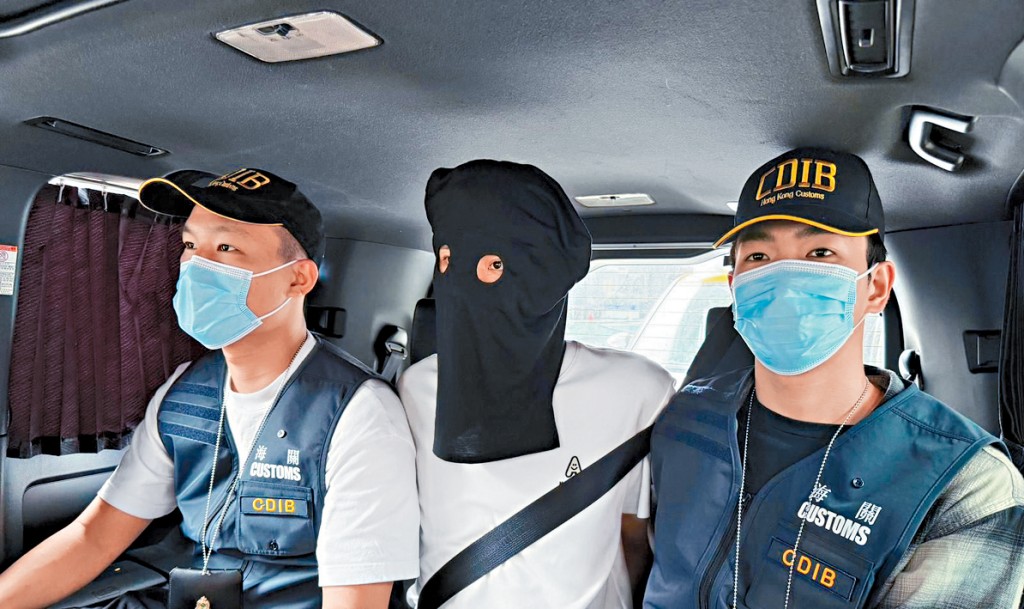 涉販毒被捕男旅客黑布蒙頭被關員押走。