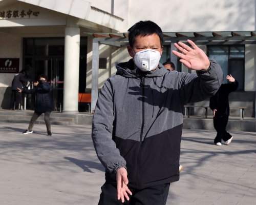 北京市民佩戴口罩在玉渊潭公园晨练。