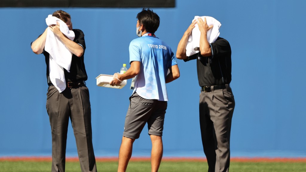 東京奧運棒球項目裁判在比赛中用大毛巾擦汗。 路透社