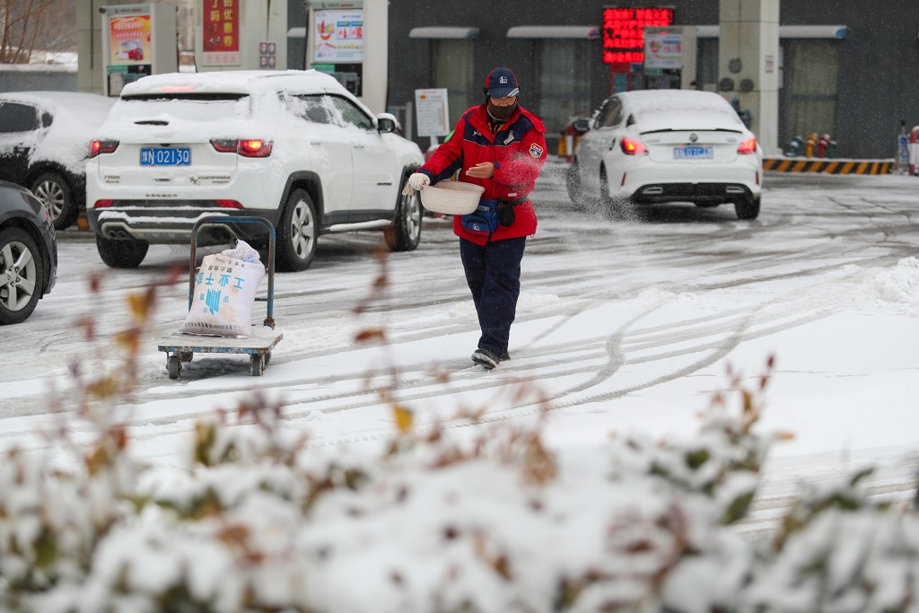 全国多地迎来降雪，2月1日，河南省商丘市的一名加油站工作人员在撒盐除雪。 新华社
