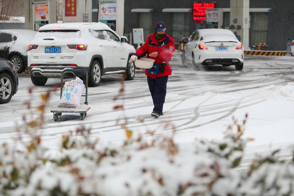 全國多地迎來降雪，2月1日，河南省商丘市的一名加油站工作人員在撒鹽除雪。 新華社