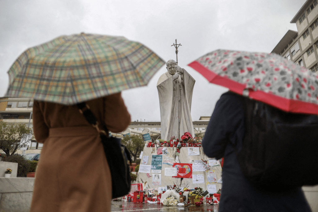 2025 年 3 月 12 日，意大利羅馬，婦女們在已故教宗若望保祿二世的雕像前，為教宗方濟各的病情祈禱。路透社