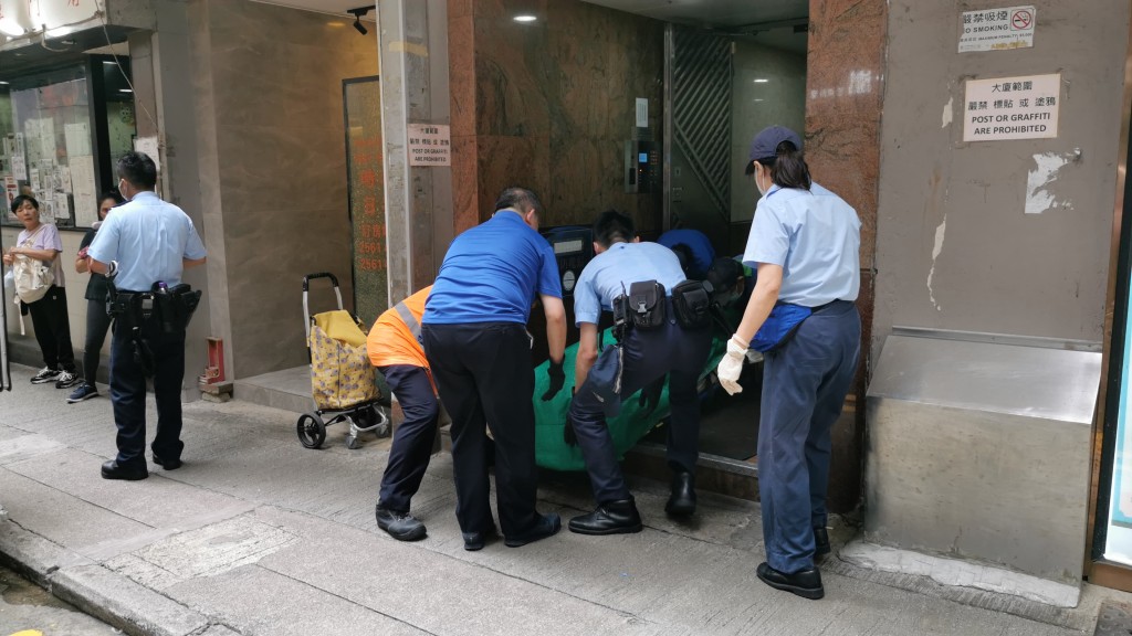 仵工與警員合力抬屍。 仵工與警員合力抬屍。
