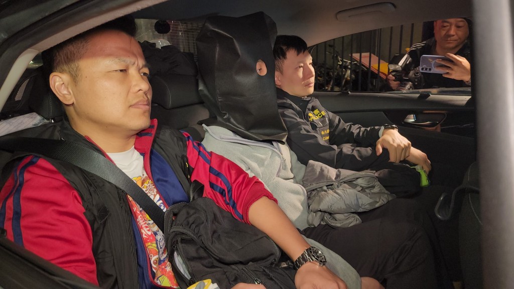 24日凌晨零時左右，其中一名被捕男子被帶上頭套，在重案組人員押解下，由便裝警車載離田心警署。黎志偉攝