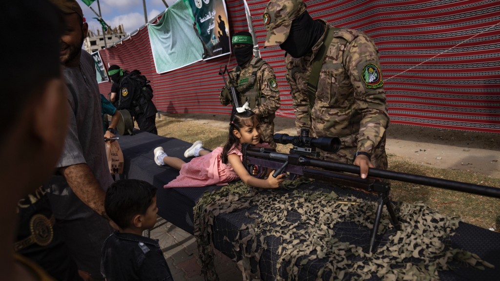 巴勒斯坦女孩在加沙走廊中部努赛拉特难民营的哈马斯「武器展」上摆姿势。 美联社