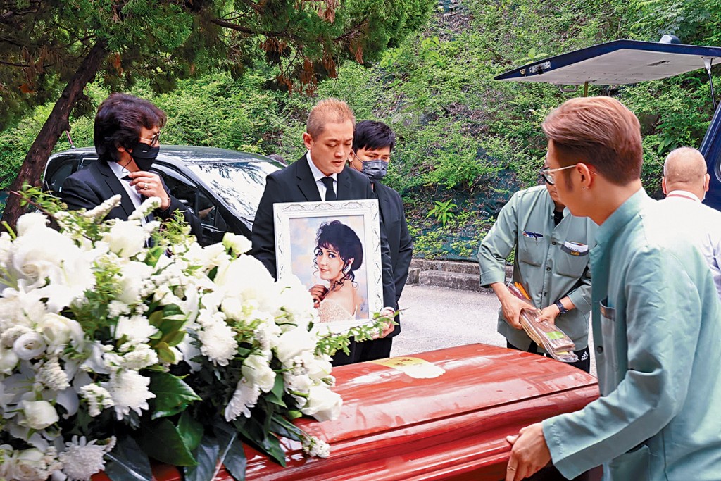 李泳漢捧亡母遺照，細佬豪仔在旁。