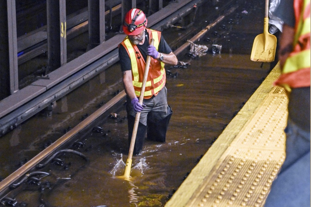 纽约时代广场的地铁轨道上，一名工作人员正在清理积水。AP