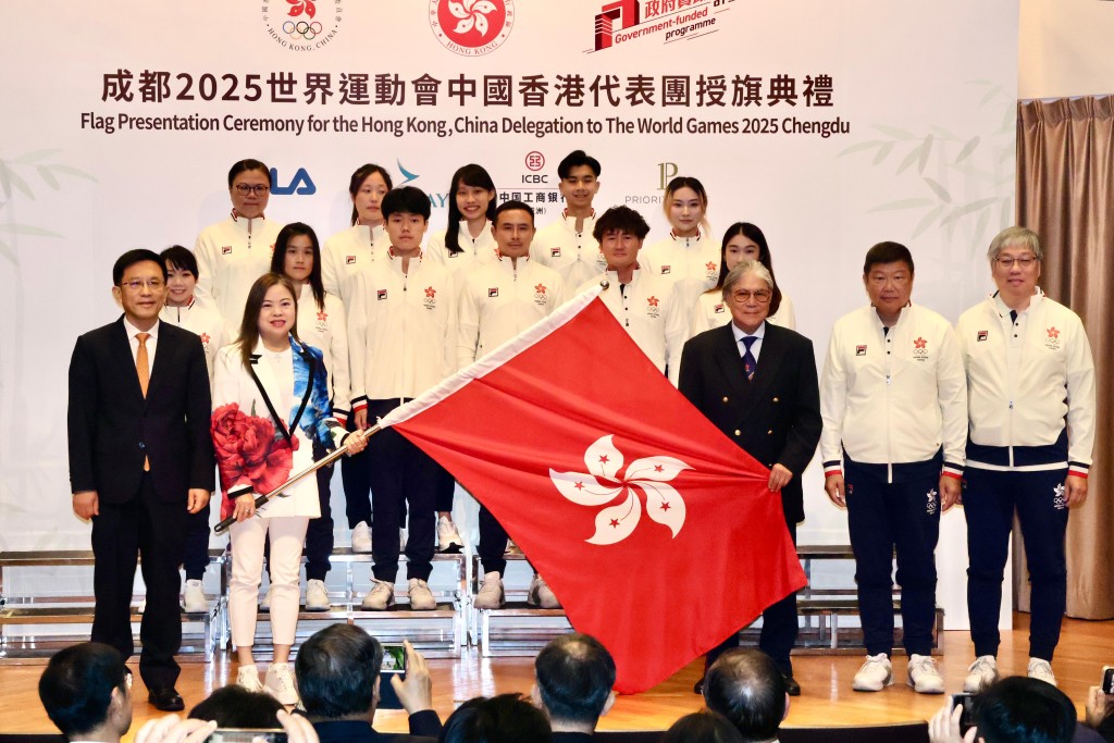 文體旅局長羅淑佩將特區旗遞交給港協會長霍震霆，港隊今屆派出22位選手參賽。徐嘉華攝