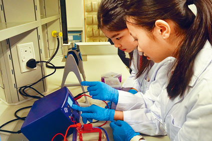 科學學會成員示範「DNA顯影實驗」，正設定高壓電源供應器進行通電。