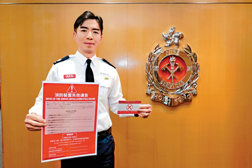 消防處消防區長（消防設施監督）馮家豪展示消防裝置「損壞告示」樣本。