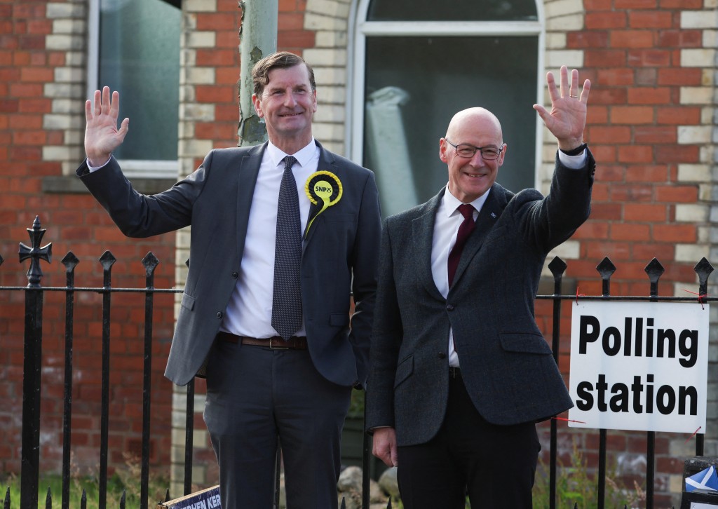 蘇格蘭民族黨(SNP) 領袖約翰·斯溫尼(John Swinney) 和當地候選人杜根(Dave Doogan) 在投票站外揮手致意。 路透社
