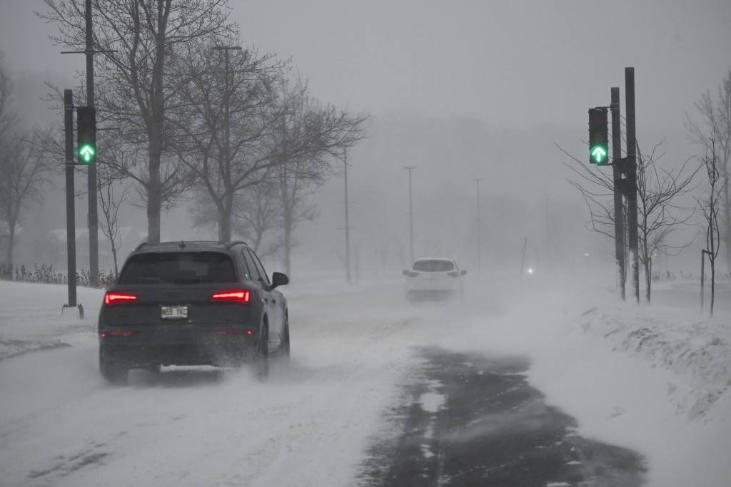 汽车冒着风雪在路上行驶。AP