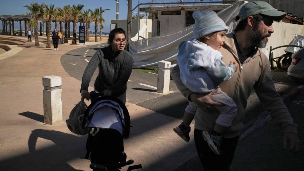 以色列空袭伊朗后，警报响起，一对夫妇带著两个孩子冲向避难所。 (美联社)