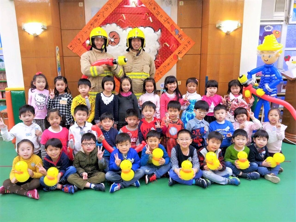 消防隊目陳義良(左)會扭小鴨氣球,哄幼兒集中精力,留心聽消防安全教育講座。(相片由香港消防處提供)
