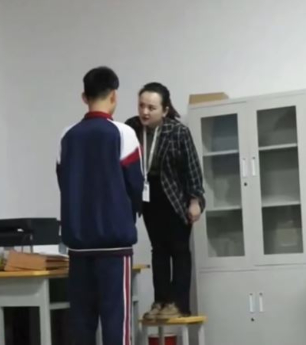 新疆有教师因与学生身高太悬殊，要站在凳上才能平视学生训话。