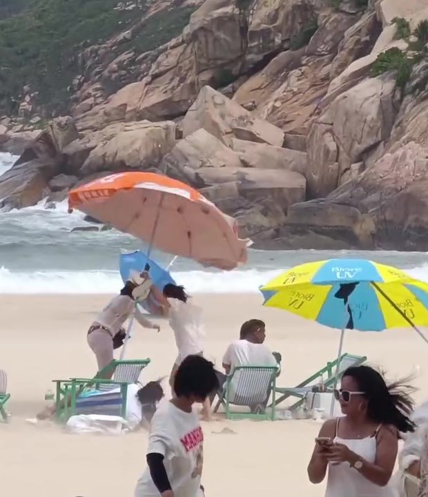 有泳客拉著太陽傘與強風搏鬥，幾乎被扯飛，情況驚險。網上截圖