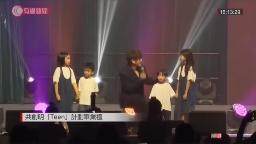 大会在他唱到《蒙着嘴说爱你》时，安排了4位小朋友到姜涛身边。（《有线新闻》截图）