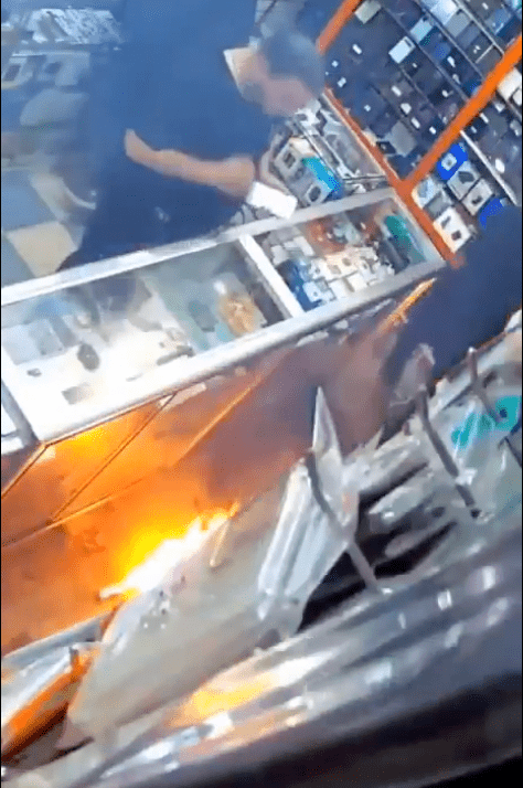 男童受驚後立即把電池拋開，店主亦顯得手足無措，急忙嘗試撲救。