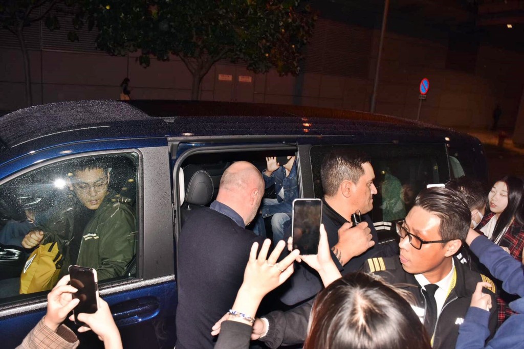 戴着口罩的张艺兴已上车，向车外粉丝挥手。