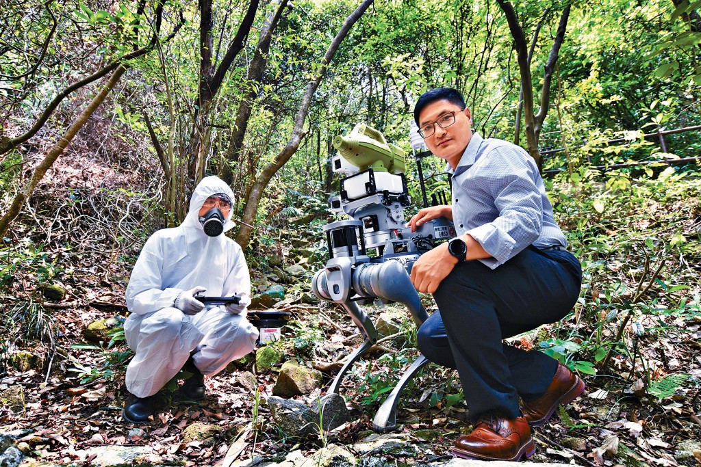 食環署將超低微量噴霧槍安裝在機械狗背上，遙距操控機械狗深入叢林及植被茂密地方等應用場景。右為孔世傑。
