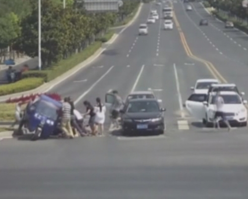 多名過司機及路人合力托起三輪車。