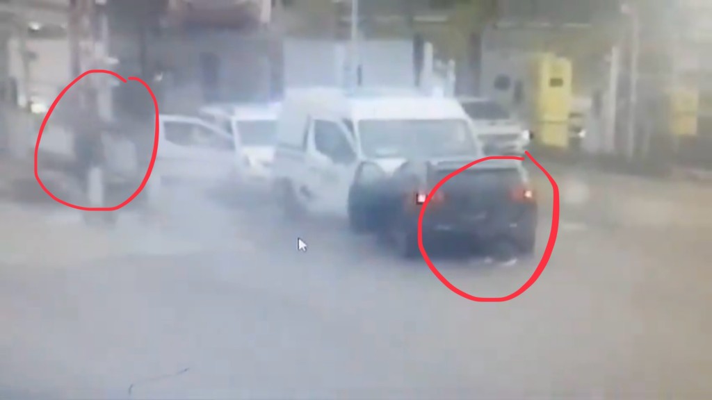 一名槍手以黑色車做掩護，另一人向囚車開槍。