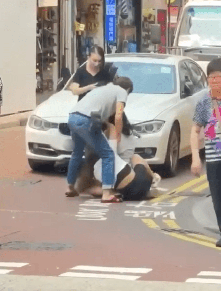 兩女仍扭作一團，黑絲襪女子上前遞手機予灰衣男。fb香港突發事故報料區網片截圖 