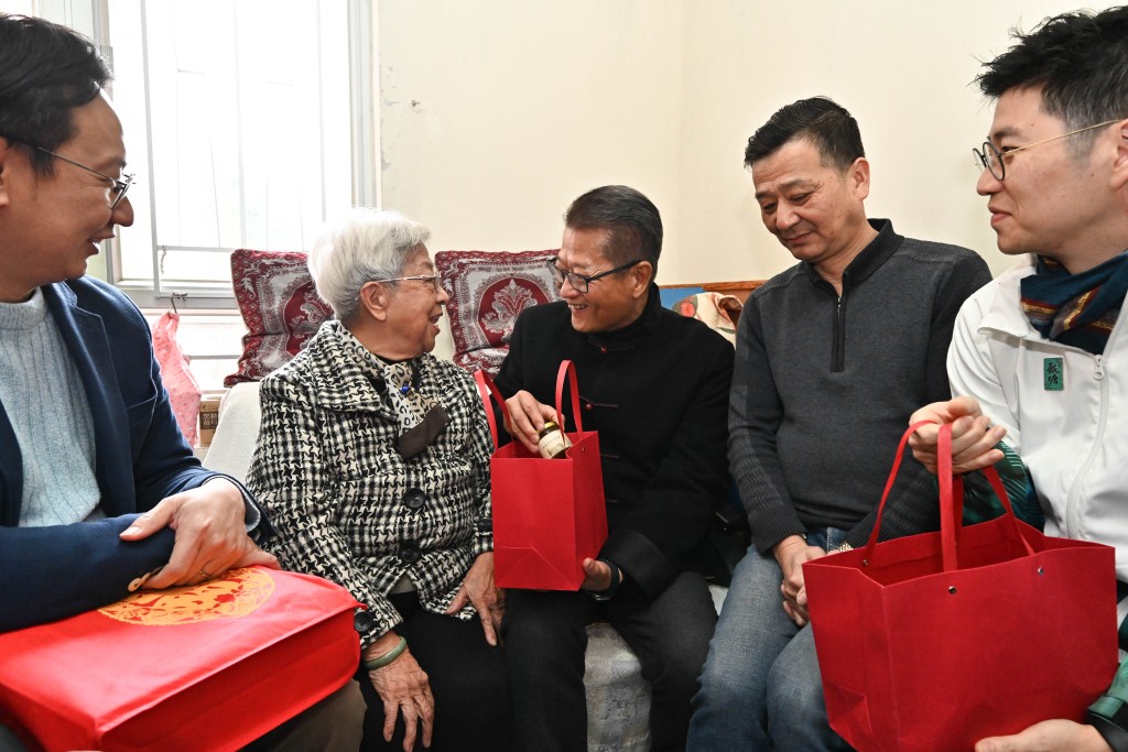 陈茂波（中）在观塘民政事务专员何立基（右三）陪同下，探访居于蓝田德田邨的家庭。政府新闻处图片