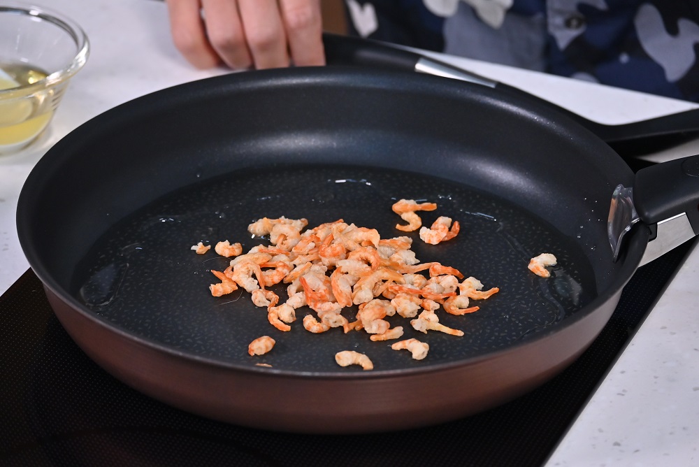 4. 起油镬，炒香虾米。Heat oil in a wok and fry dried shrimps until fragrant.