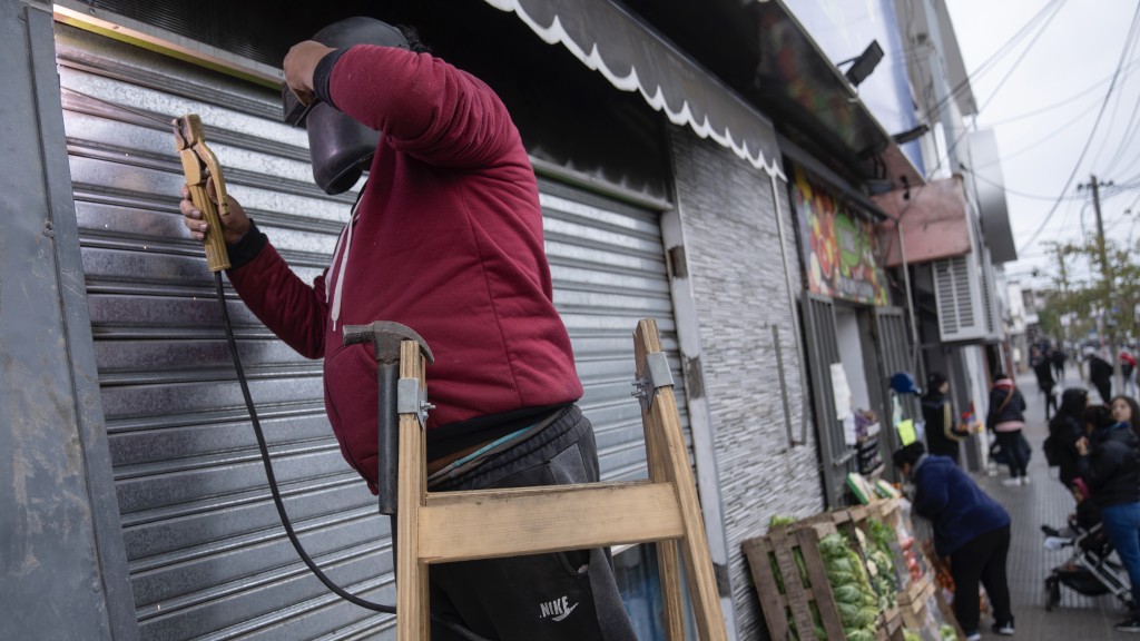 布宜諾斯艾利斯郊區一家超市受到搶劫威脅，老闆在商店入口焊接加固金屬門。 美聯社
