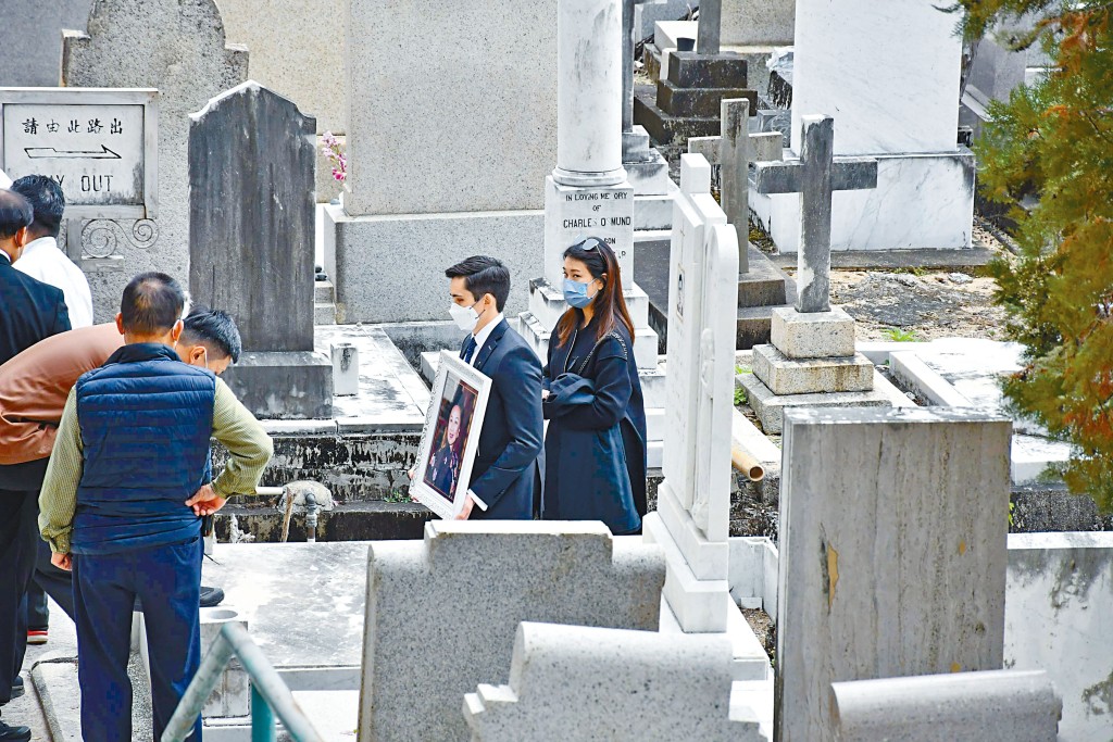 利蘊蓮兒子手捧着利孝和夫人的遺照，將外婆遺照送到棺木之上。