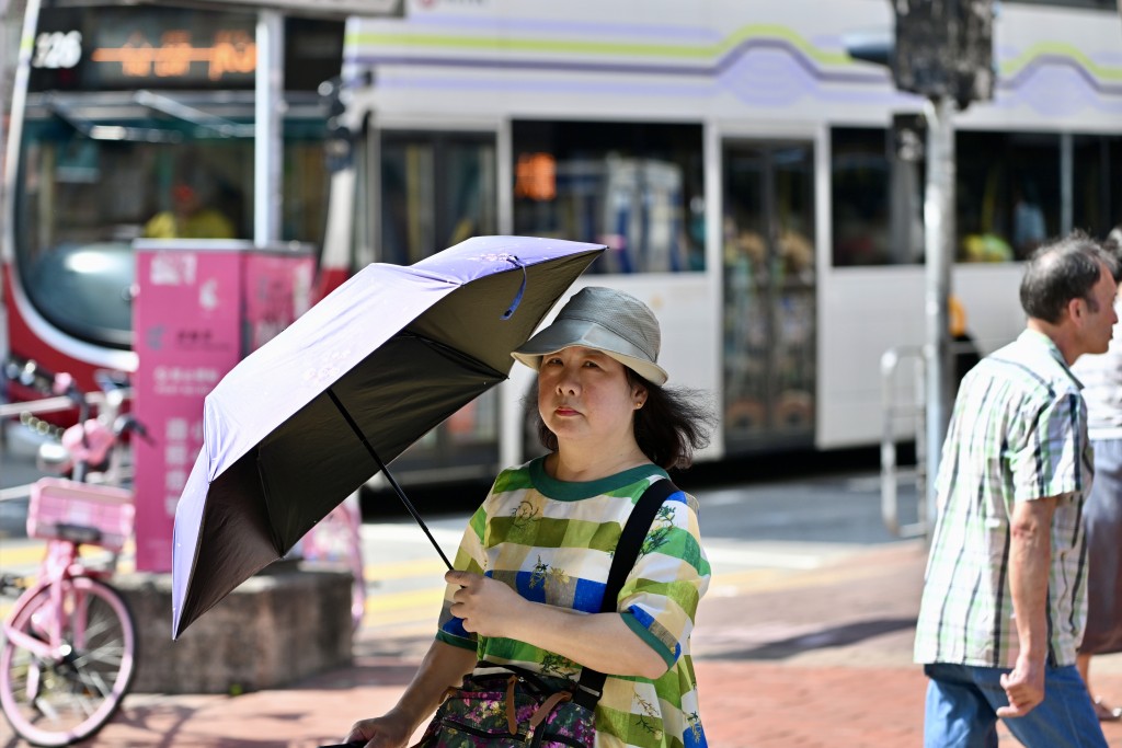 市民撐起傘防曬及戴帽防曬。劉駿軒攝 市民撐起傘防曬及戴帽防曬。劉駿軒攝