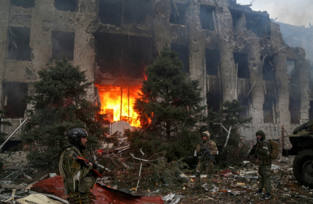 親俄軍隊人員站在馬里烏波爾一座被毀建築前。REUTERS
