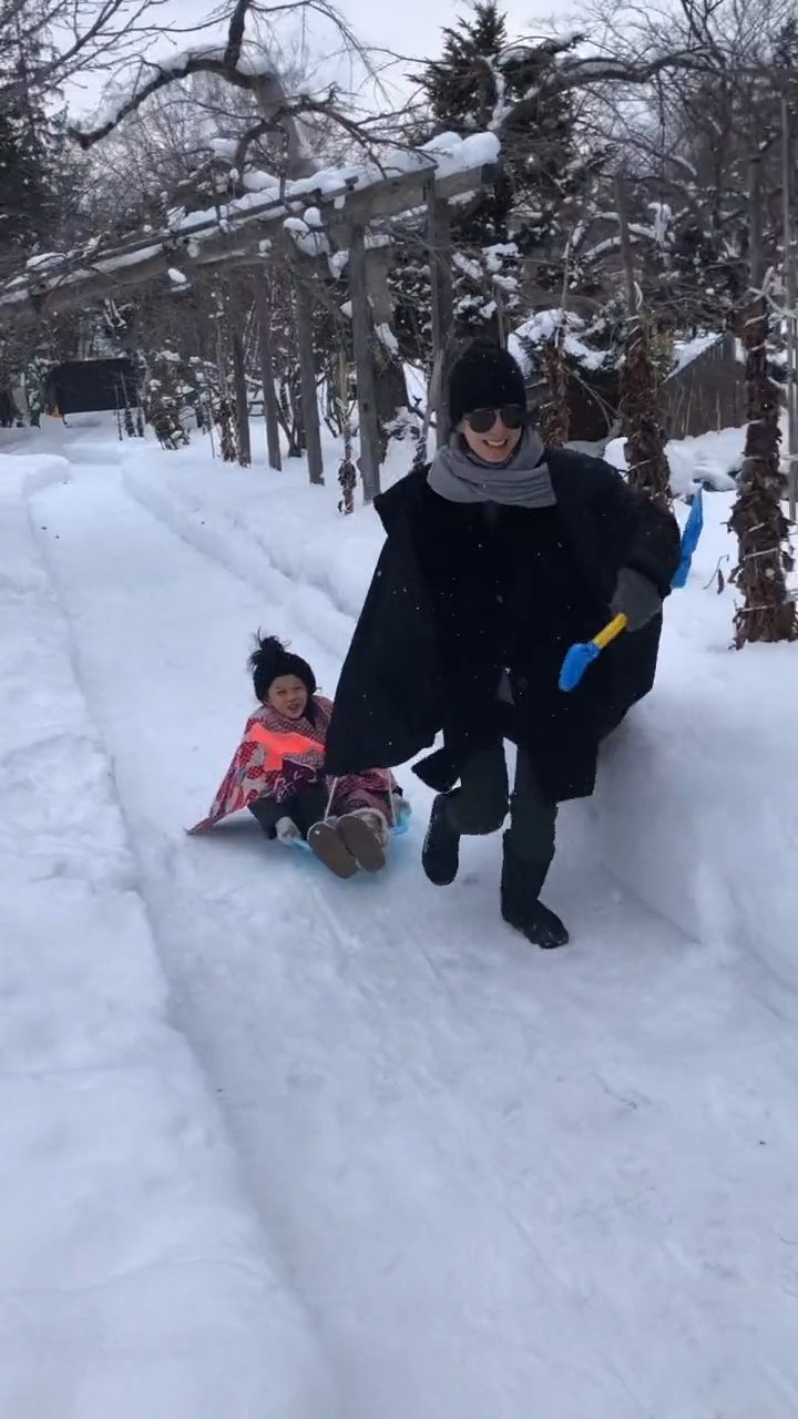 苏岩在雪地上拉住女儿玩人肉雪橇。