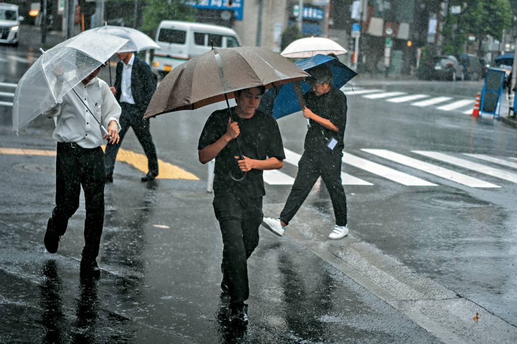東京行人昨日撐傘在街頭行走。 新華社